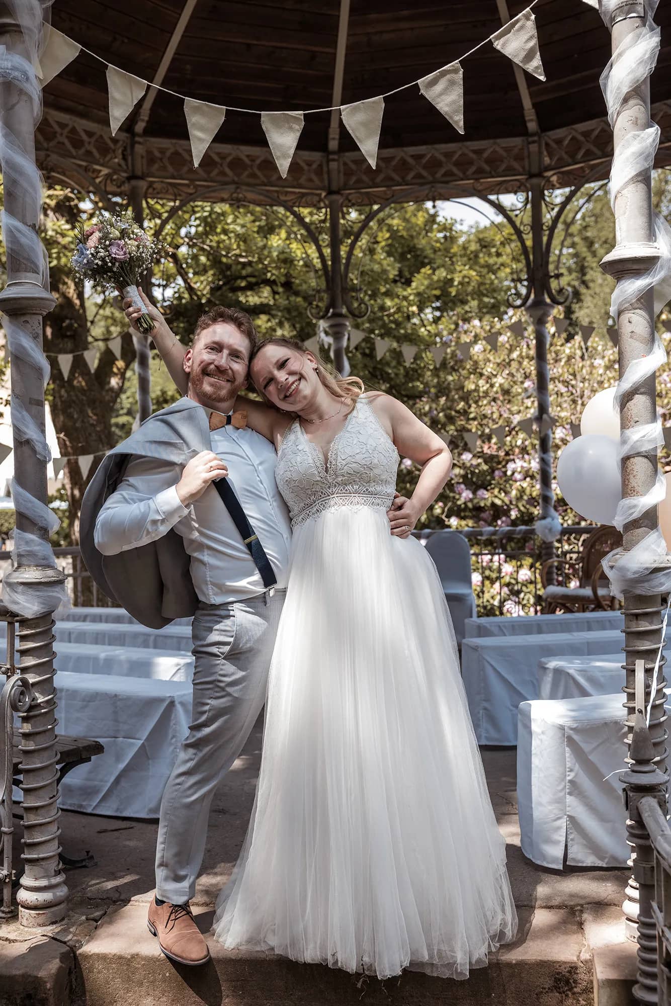 Braut in weißem Hochzeitskleid vor einem Pavillon während der Hochzeit in Freiburg.