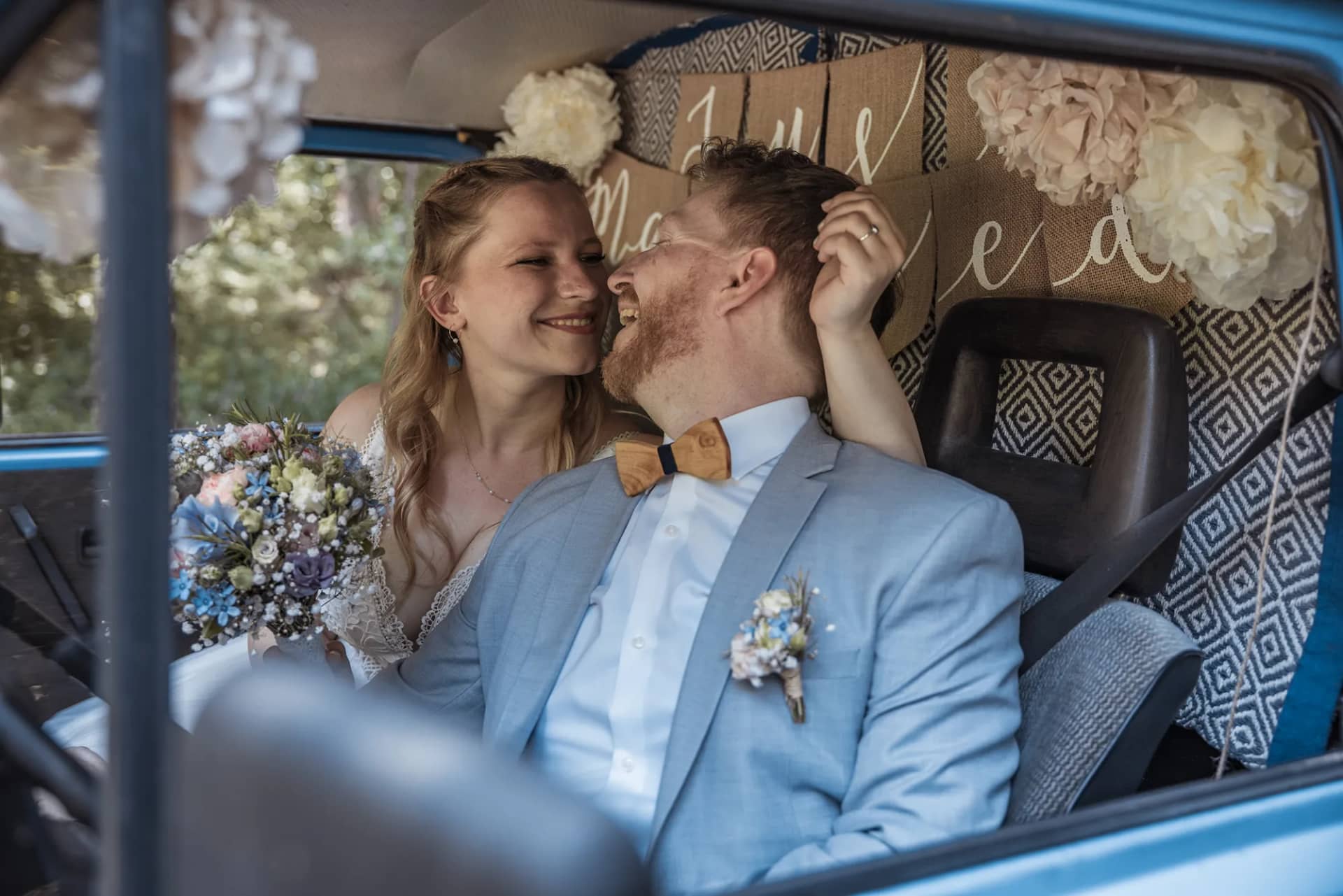 Braut und Bräutigam entspannen sich in einem blauen Auto während der Hochzeit in Freiburg.