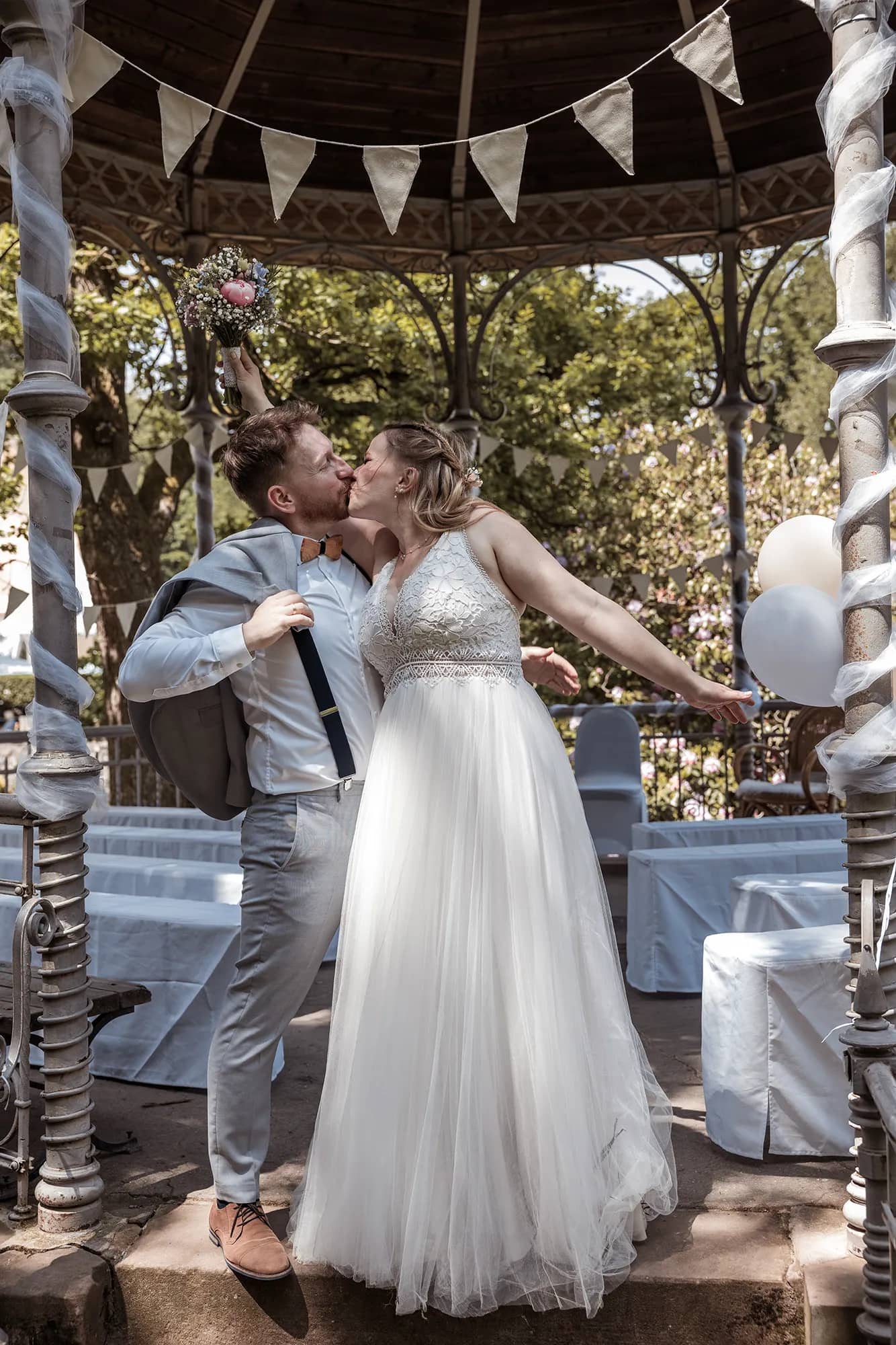 Braut in weißem Hochzeitskleid vor einem Pavillon während der Hochzeit in Freiburg.