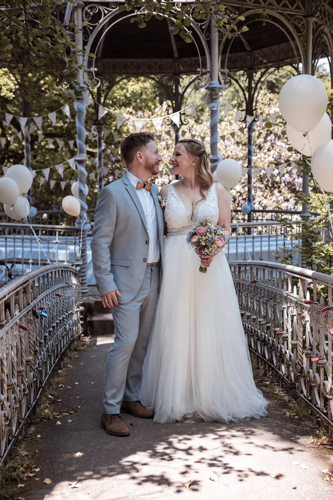 Braut in weißem Hochzeitskleid vor einem Pavillon während der Hochzeit in Freiburg.