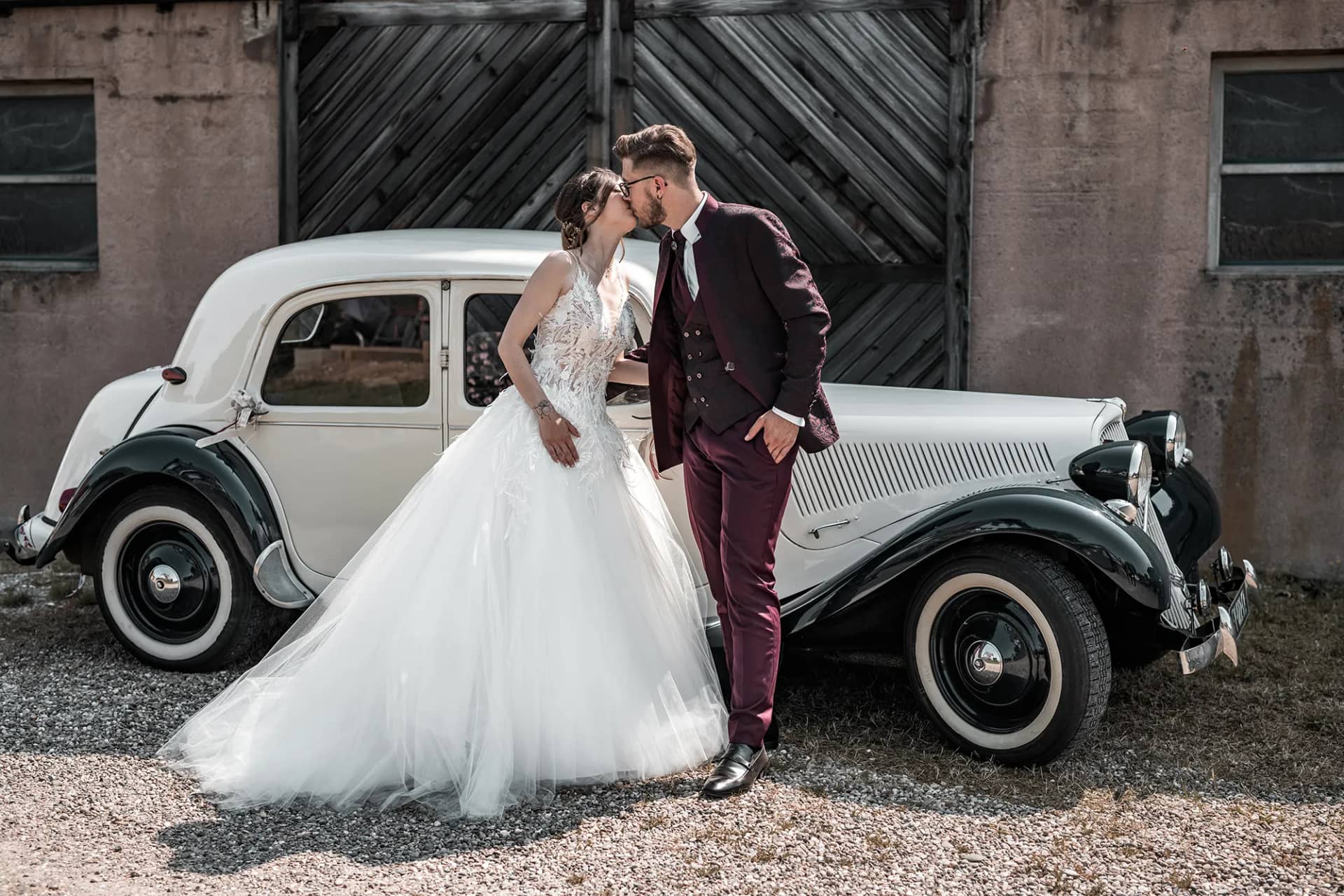 Brautpaar posiert vor einem klassischen Auto bei ihrer Hochzeit in Strasbourg, Frankreich.