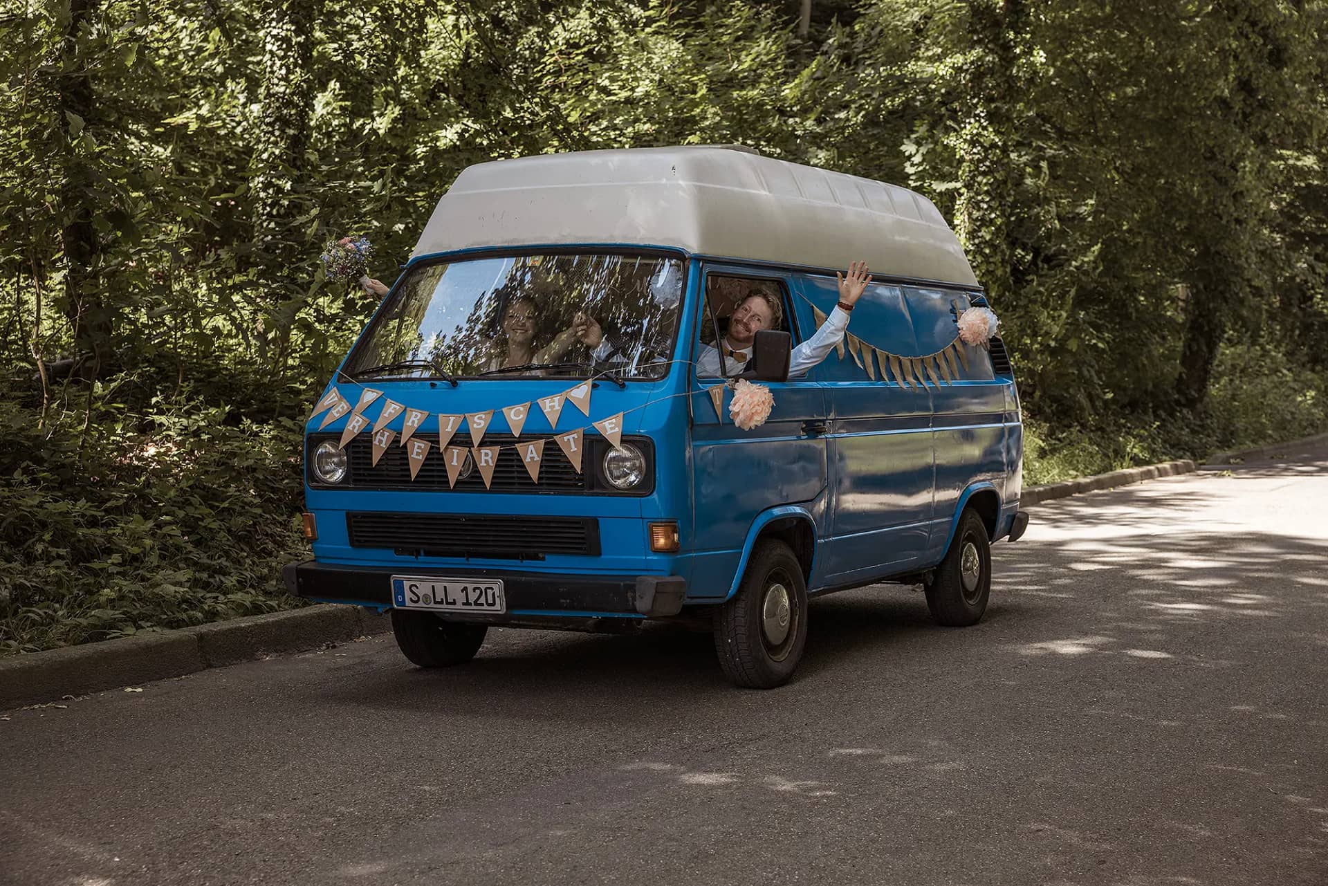 Braut und Bräutigam, fahren in ihrem Hochzeitsauto, dem VW Bus zur Hochzeitslocation am Waldsee in Freiburg
